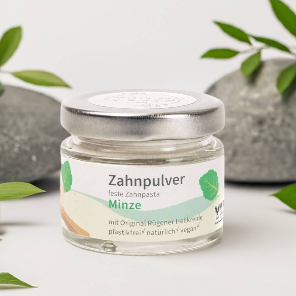 Zahnpulver Minze in Glasbehälter mit natürlicher Zutaten umgeben von Steinen und Pflanzen.
